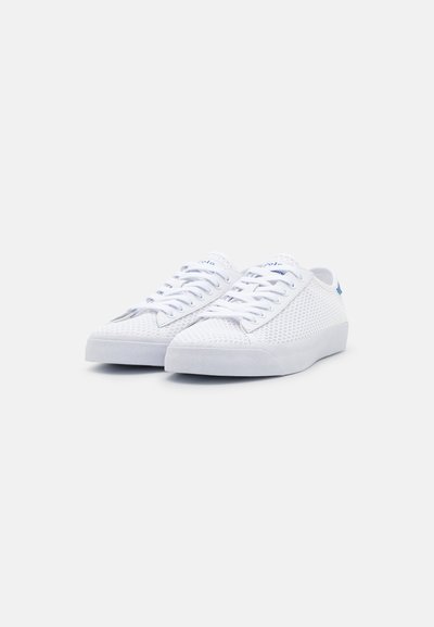 Tenis brancos com parte superior em malha, realces azuis contrastantes, língua texturizada e atacadores planos. A sola é sólida e levemente elevada.