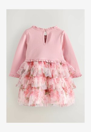 Rochie roz cu mâneci lungi, având un corp solid și o fustă din tul stratificată, cu volane și un model floral. Închidere la spate cu deschidere în formă de cheie și detaliu cu nasture.