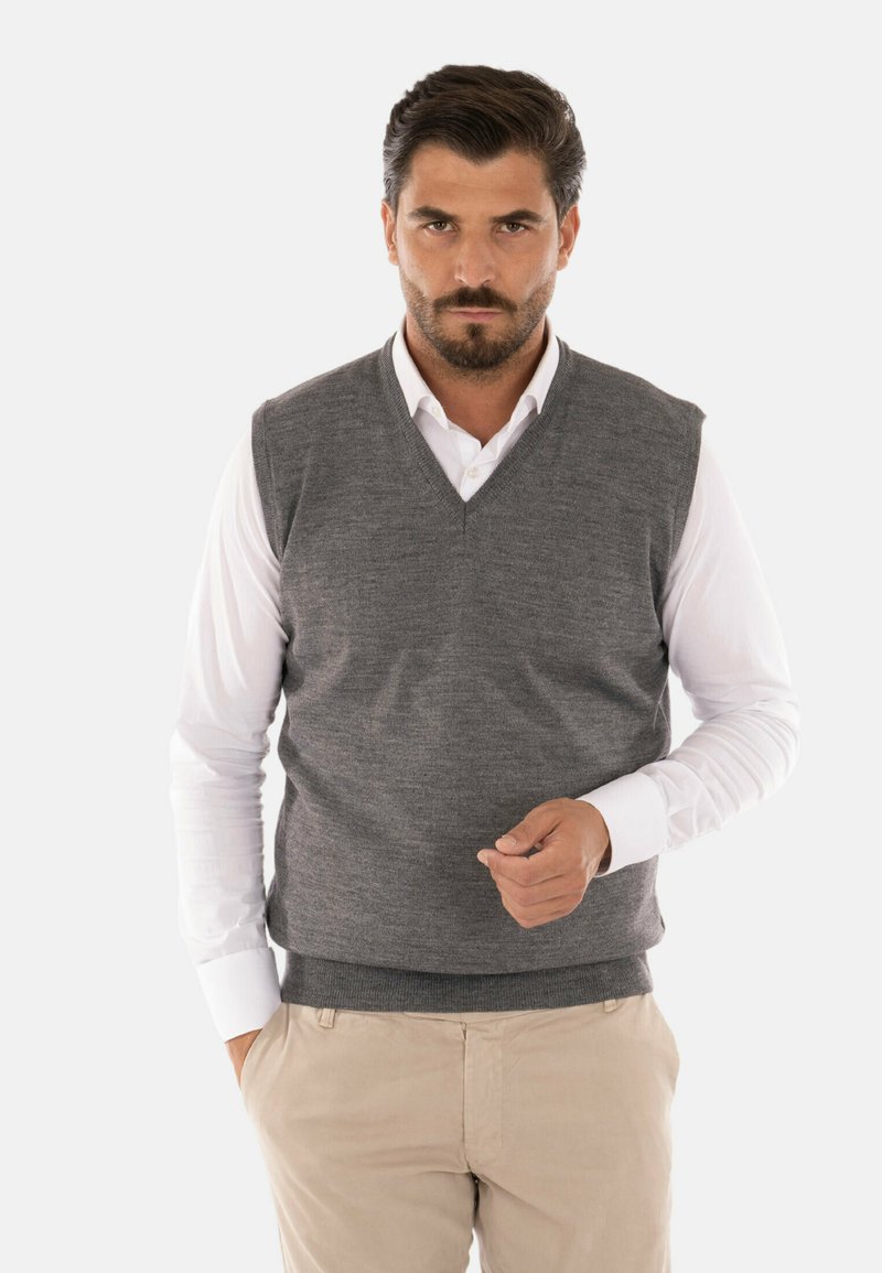Maglioncino grigio senza maniche con scollatura a V, realizzato in tessuto a maglia testurizzato, indossato sopra una camicia bianca con colletto, abbinato a pantaloni beige.