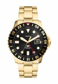 Montre Fossil avec un bracelet en acier inoxydable doré, un cadran noir, des index horaires blancs, des accents rouges et un affichage de la date. Résistante à l'eau jusqu'à 100 mètres.
