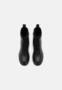 Black leather ankle boots with a smooth finish, featuring a lace-up front, side zippers, and rounded toes. The soles are textured for grip.