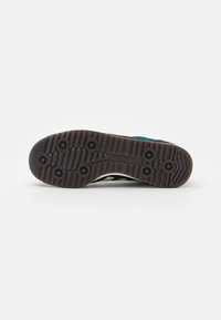 Skoled i mörkbrun gummi med cirkulära mönster och upphöjda mönster; har "adidas"-logotyp präglad på sidan.