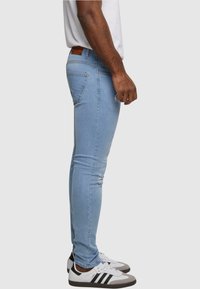 Fakó kék, skinny farmerek, látható varrással, elrontott részletekkel és egy bézs bőrpótlóval a derékrészen.