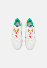 White sneakers with mesh and leather materials. Features green, blue, yellow, and red accents along with contrasting laces and logo.