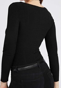 Zwart geribd top met lange mouwen, brede halslijn en een aansluitende pasvorm, gecombineerd met hooggetailleerde zwarte broek en een smalle zwarte riem.