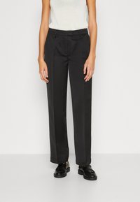Black tailored pants with a straight leg fit, made of smooth fabric. Features a flat front and belt loops. Paired with black loafers.