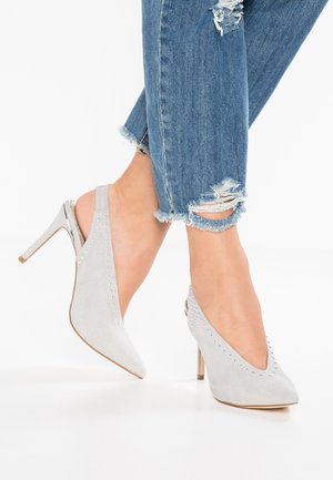 Décolleté slingback in suede grigio con punta affilata, dotate di accenti in metallo argentato e un tacco metallico. Indossati con jeans blu sfilacciati.