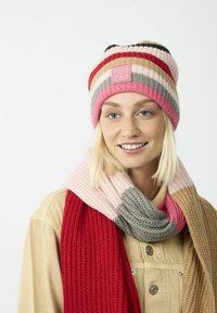 Strickmütze mit horizontalen, mehrfarbigen Streifen in Rosa, Rot, Creme und Grau. Begleitet von einem strukturierten, mehrfarbigen Schal.