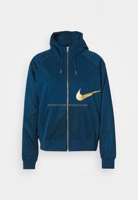Mörkblå zip-up hoodies med huva, framfickor och stor gyllene Nike-swooshlogga på vänster bröst.