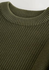 Pull en tricot vert olive avec un motif texturé, présentant un col rond côtelé et des accents en panneaux lisses sur un côté.