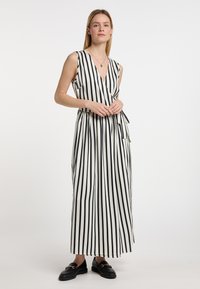 Maxi mekko mustavalkoisilla pystyraidoilla, syvällä V-kaula-aukolla, solmittavalla vyöllä ja pehmeällä kankaalla. Yhdistetty mustiin mokkasiineihin.