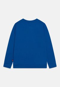 Långärmad skjorta i solid blå bomull, med rund halsringning, ribbade ärmslut och en liten logotypetikett på nedre vänstra sidan.