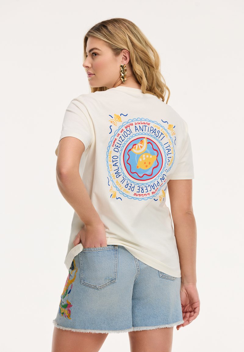 Crème kleurig t-shirt met korte mouwen en een kleurrijke grafische afbeelding van voedsel op de achterkant. Gecombineerd met lichte denim shorts, voorzien van borduring aan de zijkant.
