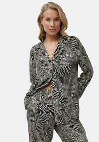 Schwarz-weiße gestreifte Schlafanzugset, bestehend aus einem kollarierten Knopfhemd mit Tasche und passenden Hosen mit elastischem Bund. Glatter Stoff.