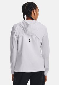 Witte lichtgewicht jas met capuchon, voorzien van een ontwerp op de achterkant met horizontale zwarte strepen. Gladde textuur en elastische manchetten.