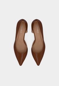 Καφέ δερμάτινα ψηλοτάκουνα παπούτσια με μυτερή μύτη, λεία υφή και σχεδιασμό με ανοίγματα στα πλάγια. Το εσωτερικό διαθέτει μπεζ φόδρα.