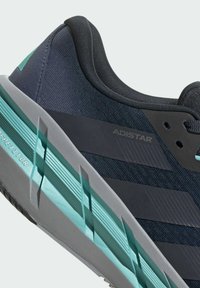 Baskets de sport bleu foncé avec un dessus texturé, présentées avec des accents cyan et une semelle intermédiaire grise. Le nom de la marque "ADISTAR" est visible sur le côté.
