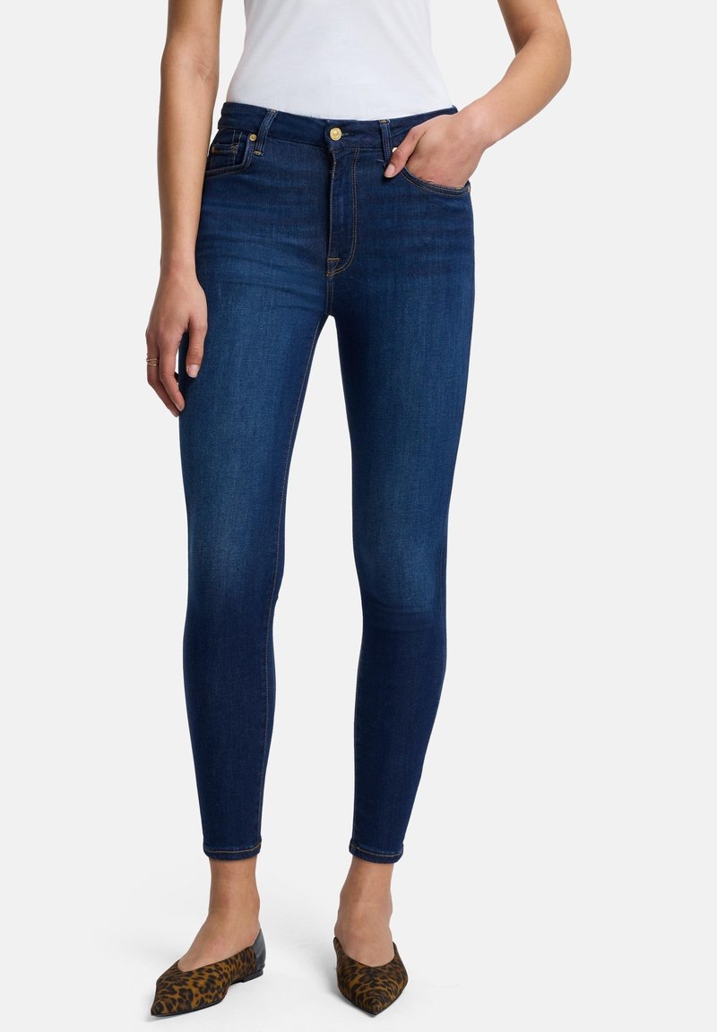 Smal jeans i mörkblå denim med hög midja. Har en framficka och guldfärgade detaljer. Bärs med djurmönstrade spetsiga ballerinaskor.