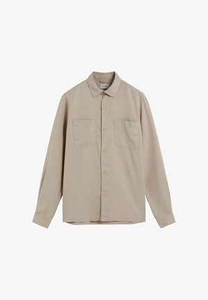 Chemise beige à manches longues avec col, deux poches avant et fermeture à boutons. Fabriquée en tissu lisse avec une texture minimale.