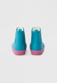 Bottes en caoutchouc bleues jusqu'à la cheville avec des semelles roses, dotées d'une doublure douce, d'une texture lisse et d'une languette à l'arrière pour un enfilage facile.