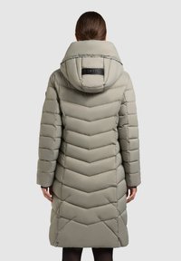Podložena siva parka z vzorcem v chevron, velika kapuca in logotip na hrbtu. Dolgi rokavi, zasnova do kolen.