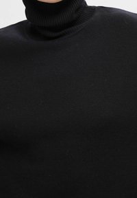 Zwarte coltrui, geribbelde textuur, aansluitend model, zachte stof, hoge hals, geen zichtbare patronen of hardware details.