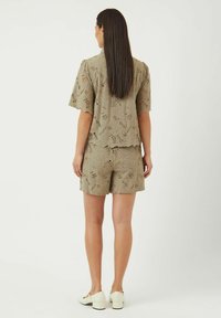 Beige blonde topp og shorts-sett med blomstermønster, korte ermer og bølgede kanter, kombinert med hvite blokk-hæl-sko.