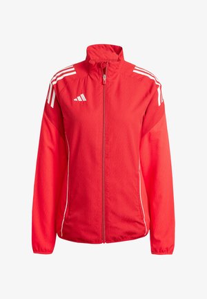 Rode sportjack gemaakt van lichtgewicht stof met een volledige rits. Heeft witte strepen op de schouders en zijkanten, en een hoge kraag.