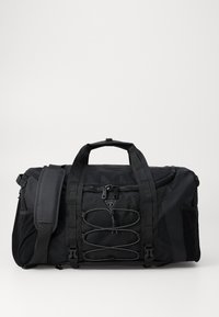 Sac de sport noir en tissu durable, doté de plusieurs sangles, de poches zippées et d'un cordon bungee décoratif à l'avant.
