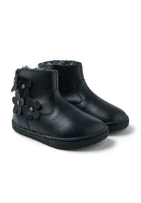 Botas de tobillo de cuero negro con forro de pelo sintético, que presentan flores de fieltro negro con acentos de rhinestones en el lado. Textura suave, diseño casual.