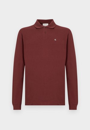 Vínová polokošile s dlouhým rukávem vyrobená z bavlny, s klasickým límečkem, zapínáním na tři knoflíky a malou vyšitou nášivkou na hrudi.