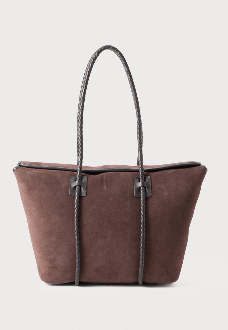 Sac fourre-tout en suède marron avec des poignées tressées couleur marron foncé, offrant un design spacieux et des accents matériels minimaux. Fini texturé.