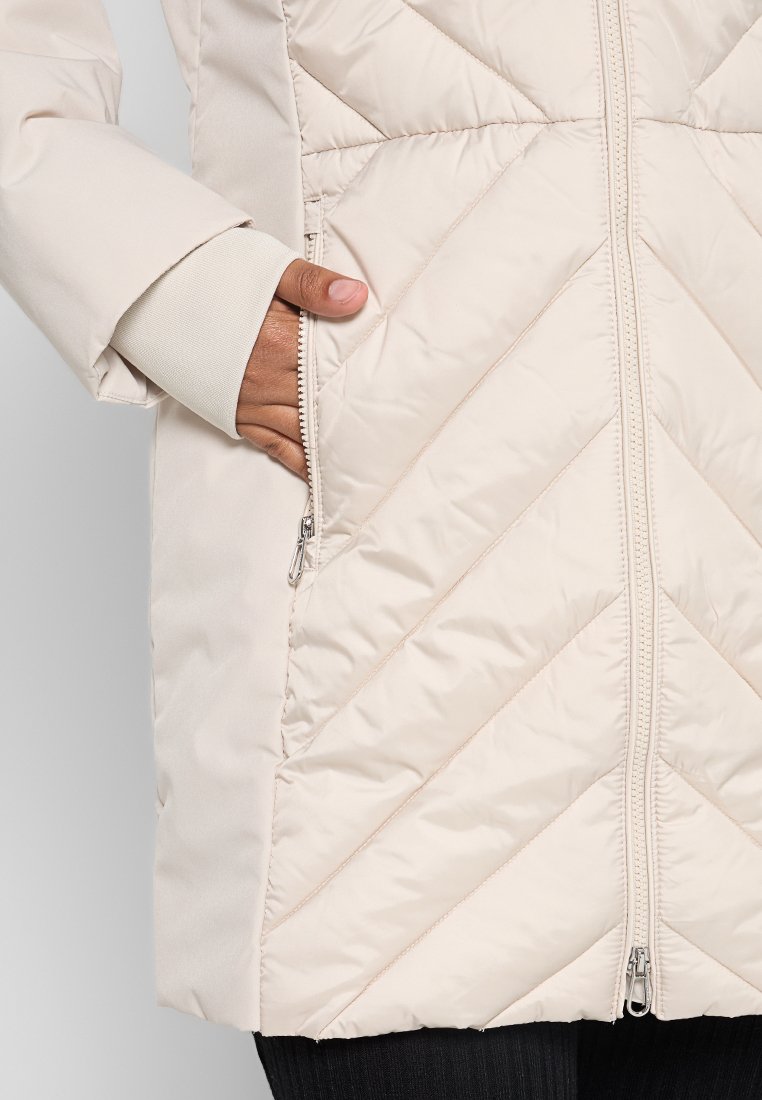 Hellbeige gepolsterte Jacke mit Zickzackmuster, Frontreißverschluss und Seitentaschen. Verfügt über eine glatte Textur und gerippte Bündchen.