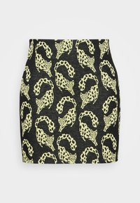 Mini-jupe noire avec un motif répété de léopards et de chats en jaune. Tissu doux avec une silhouette ajustée et une taille élastique.