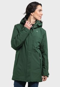 Green waterproof jacket with a hood, featuring a front zipper, side pockets, and a logo detail on the chest, made of smooth, durable fabric.