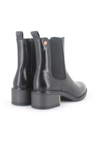 Botas de cuero negras hasta el tobillo con paneles laterales elásticos, punta redondeada y un tacón bajo en bloque que presenta un acento dorado cerca del tacón.