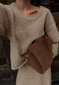 Beige oversize tröja i en mjuk, stickad textur tillsammans med en slapp brun mockaväska med rundade hörn och minimalistisk design.