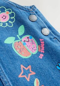 Tessuto in denim con grafiche colorate, inclusa un'illustrazione di un frutto sorridente, fiori e stelle. Include bottoni a pressione in metallo.