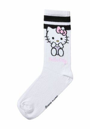 Chaussette blanche mi-mollet avec deux rayures noires et un personnage Hello Kitty assis avec un nœud rose près du haut du revers.