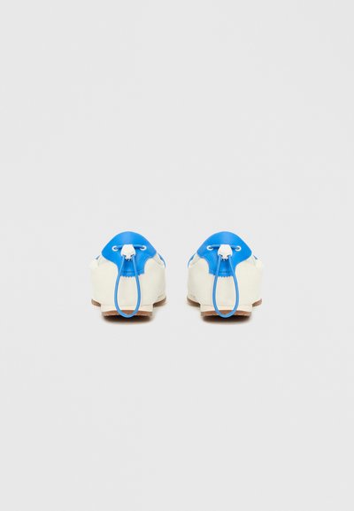 Υποδήματα με κρεμ βάση και μπλε δερμάτινες λεπτομέρειες, στρογγυλεμένο σχήμα, κορδόνια και υφή στην επιφάνεια. Ορατή η σόλα από καουτσούκ.