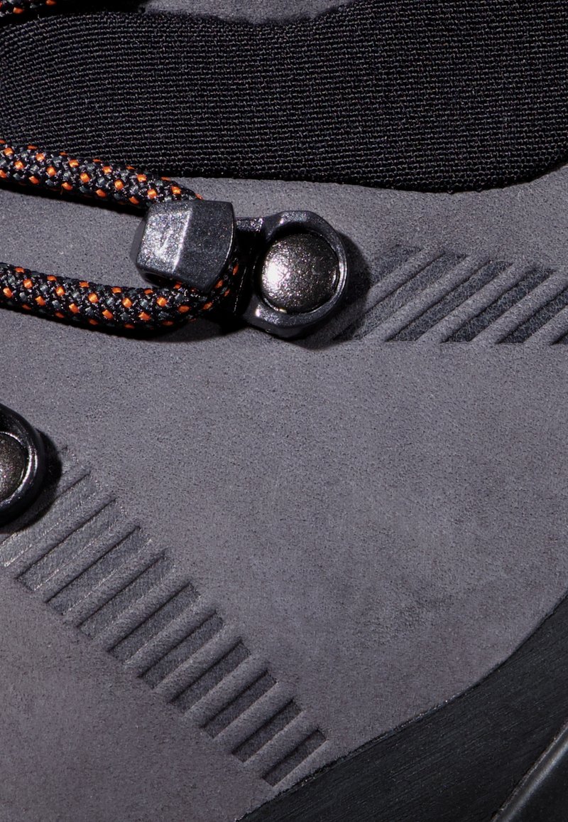 Scarpa da esterno in suede grigio con parte superiore in tessuto nero, suola in gomma testurizzata, accessori rotondi neri e lacci a motivo nero-arancio.