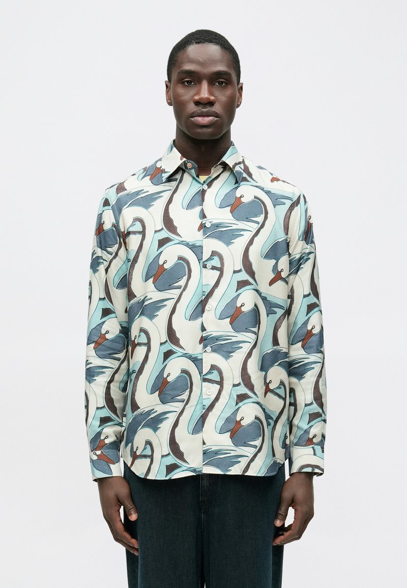 Košeľa s dlhými rukávmi z ľahkej tkaniny obsahuje vzor labute a vĺn v modrých, bielych a hnedých tónoch, s zapínaním na gombíky vpredu a golierom.