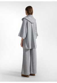 Grijze, oversized hoodie met een zachte textuur en capuchon, gecombineerd met wijde broekspijpen, beide met een gemêleerd patroon.
