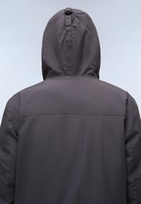 Grijze capuchonjack met een matte afwerking, een strakke capuchon en een naad over de rug, ontworpen voor buitenactiviteiten.