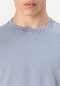 Blå bomulds T-shirt med rund halsudskæring og glat tekstur samt ribbet krave. Enkel, ren design uden synlige mønstre eller grafik.