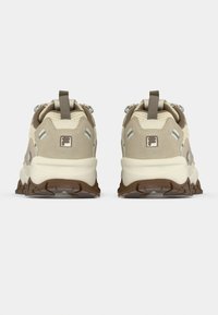 Αθλητικά παπούτσια σε μπεζ και κρεμ αποχρώσεις με υφή στην επάνω επιφάνεια, λεπτομέρειες από TPU και καφέ λαστιχένια σόλα. Διαθέτουν θηλιά για εύκολη εφαρμογή.