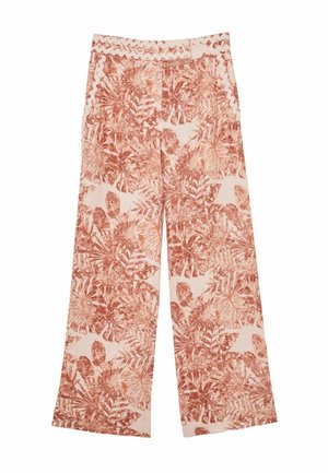 Close-up af maveparti med bukser med blomsterprint og rickrack-kant båret af en person med blottet mave og den ene hånd synlig.