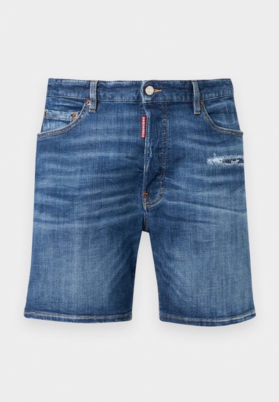 Shorts en denim bleu avec poches avant, fermeture à boutons, passants pour ceinture, légère usure sur la cuisse droite, et une étiquette de marque rouge près de la fermeture éclair.