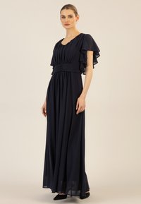 Marineblaues Maxikleid mit kurzen Rüschensäumen, einem gerafften Oberteil und einer taillierten Taille. Weicher Stoff mit einem fließenden Rock und leichtem Glanz.