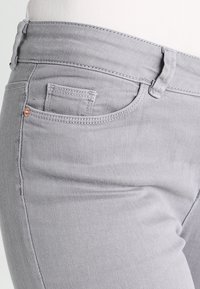 Grijze denim jeans met een slim fit, klassiek vijf-pocket ontwerp en subtiele stikdetails. De stof heeft een gladde textuur.